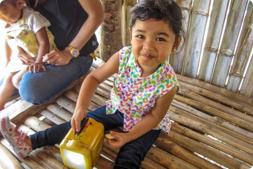 Petite fille jouant avec une lampe solaire aux Philippines, projet de HSSI