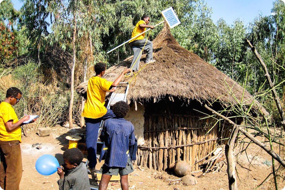 Technician installing a solar panel on a rural house, solar village project