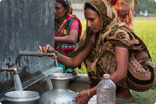 Women filling a jar with watter in a village in rural Asia