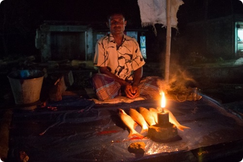 Vendeur de poisson au Cambodge s'éclairant avec une lampe à kérosène